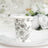 Floral design paper cup on a white plate with elegant table setting.