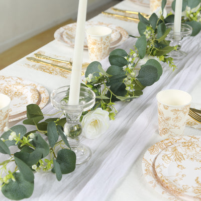 Elegant table setting with floral plates, candles, and greenery.