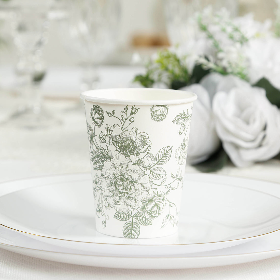 Floral design paper cup on a decorative plate in a table setting.