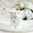Floral design paper cup on a decorative plate in a table setting.