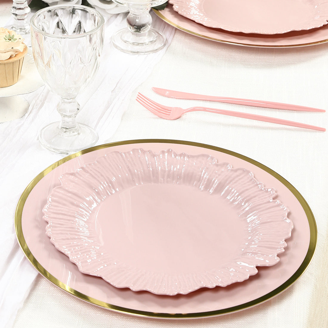 Pink decorative plates with a gold rim on a dining table setting.