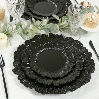 Black textured plates stacked on a table with decorative elements.