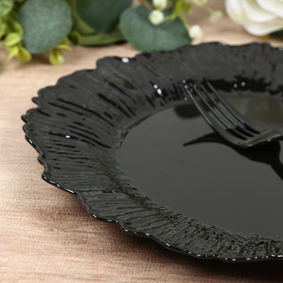 Black textured ceramic plate with a decorative edge and fork on a wooden table.