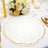 Elegant white plate with gold rim on a dining table with floral centerpiece.