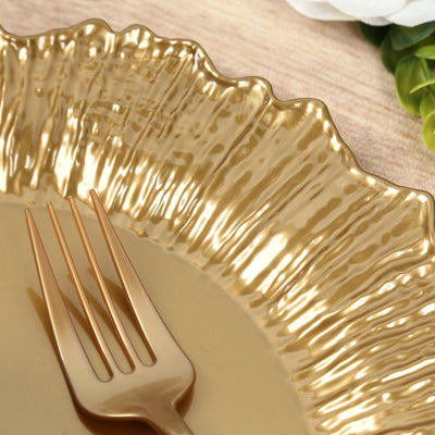 Gold decorative plate with textured edge and golden fork on wooden table.