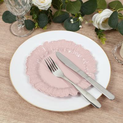 Pink decorative plate with silver cutlery on a wooden table setting.