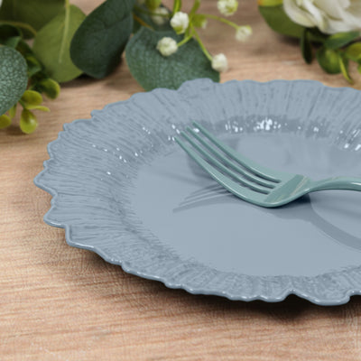 Grey scalloped plate with a fork on a wooden table setting.
