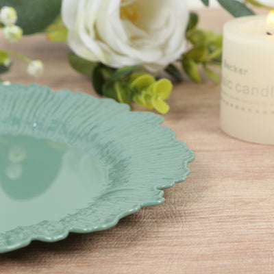 Green decorative plate with textured rim beside a candle and flowers.