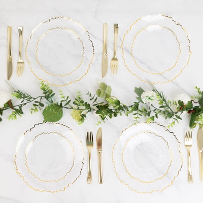 Elegant glass plates with gold trim and cutlery arranged on a marble table.