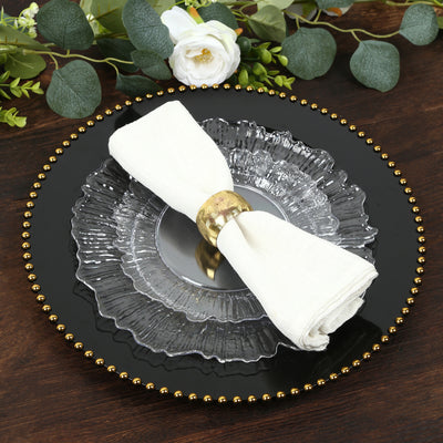 Elegant table setting with glass plates and a linen napkin.