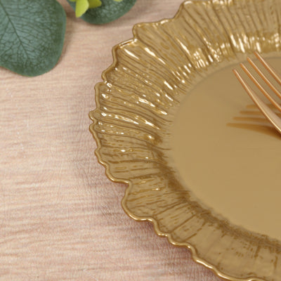 Gold scalloped plate with elegant texture and a fork on a wooden surface.
