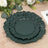 Dark green decorative plates stacked on a wooden table with greenery