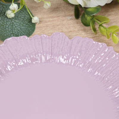 Pink decorative plate with a ruffled edge against a natural wood surface.