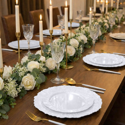 Elegant dinner table set with white plates, candles, and floral decorations.