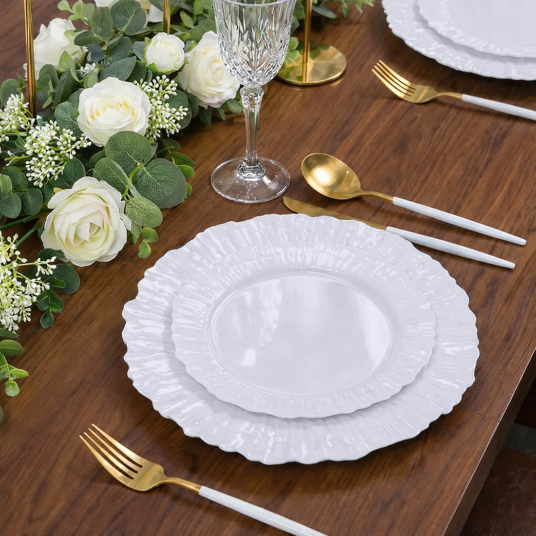 Elegant white dinner plates set on a rustic wooden table with floral decor.
