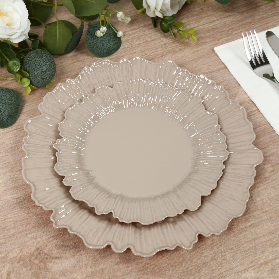 Set of elegant beige decorative plates with ruffled edges on a wooden table.