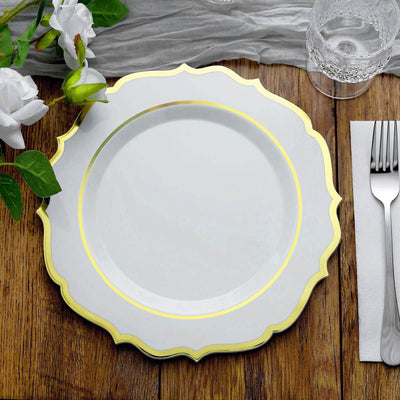 Elegant white plate with gold trim on a wooden table setting.