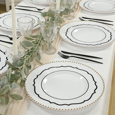 Elegant white dinner plates with black accents and gold trim on a beautifully set table.