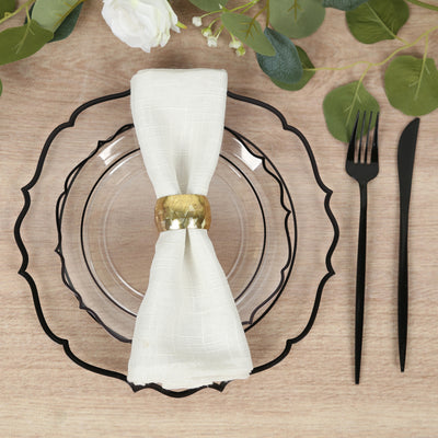 Elegant table setting with a clear plate, white napkin, and gold napkin ring.