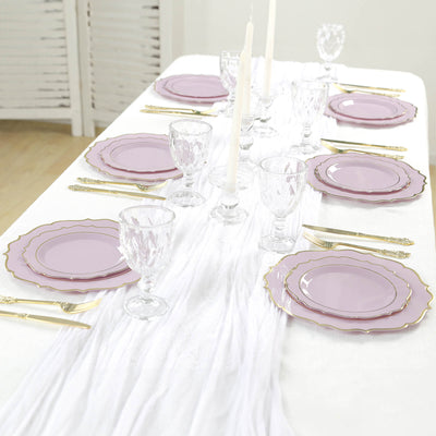 Elegant purple dinnerware set with crystal glassware on a white tablecloth.