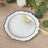 Elegant white plate with black rim and gold fork on wooden table.