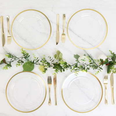 Elegant dinner table setting with gold-rimmed plates and greenery decor.