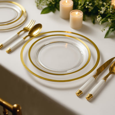 Elegant gold-rimmed glass plates set on a table with candles and greenery.