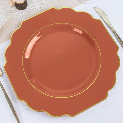 Elegant scalloped orange plate with gold trim on a table setting.