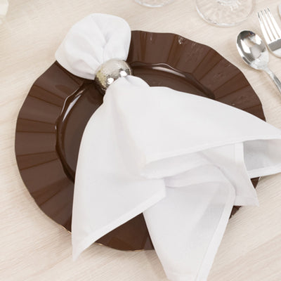 Elegant white napkin with silver ring on a brown plate.