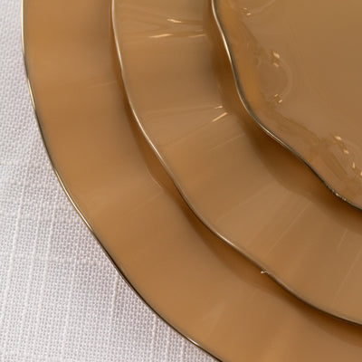Elegant beige dinner plates with gold trim stacked together.