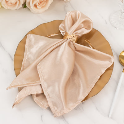 Elegant satin napkin tied with a gold ring on a decorative plate.