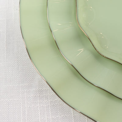 Green vintage plates with gold trim stacked elegantly.