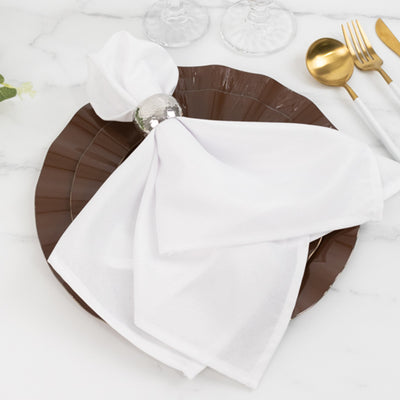 Elegant white napkin tied with a silver ring on a brown plate setting.