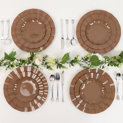 Brown decorative plates arranged with cutlery and greenery.