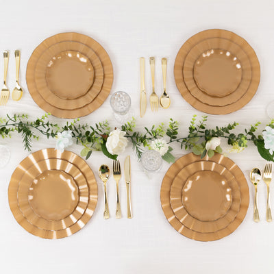 Elegant golden plates set on a table with greenery and floral accents.