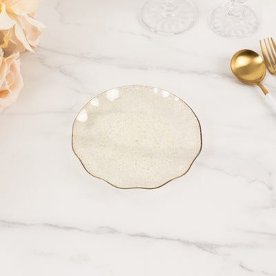 Elegant decorative plate with a scalloped edge and gold rim on a marble surface.