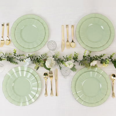 Elegant green dinner plates set on a table with gold cutlery and floral accents.