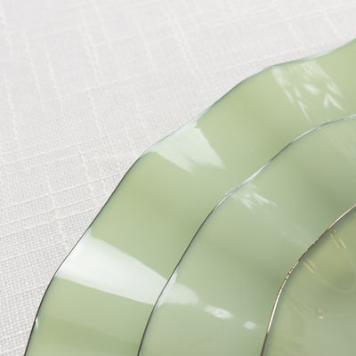 Elegant green ceramic plates stacked on a textured white tablecloth.