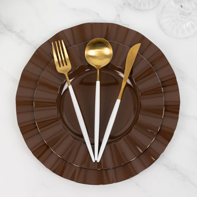 Brown plate with gold cutlery on a marble surface.