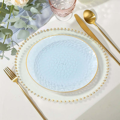 Elegant blue glass plate with gold rim and beaded edge, styled on a table setting.