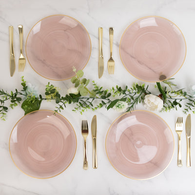 Elegant pink dinner plates with gold rims arranged on a marble table setting.