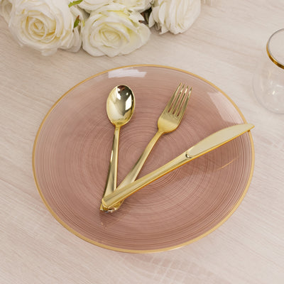 Gold cutlery set on a pink plate with elegant design.