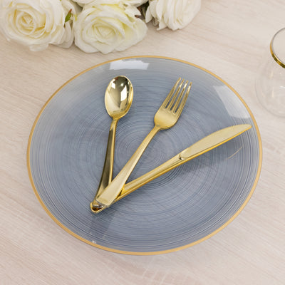 Elegant gold cutlery on a blue decorative plate with a floral backdrop.