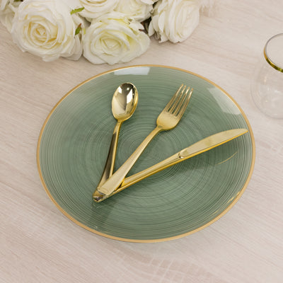 Gold cutlery on a green plate with gold rim, styled with white roses in the background.