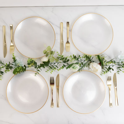 Elegant dining set with white plates and gold cutlery on a marble table.