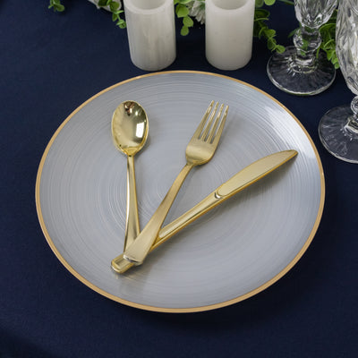 Gold cutlery on a gray plate, elegantly arranged for dining.