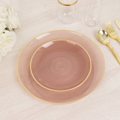 Elegant pink and gold dinner plate on a light wooden table.