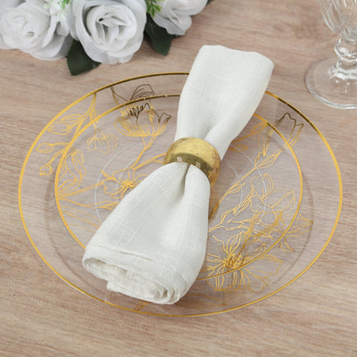 Elegant golden floral plate with white napkin and gold ring on wooden table.