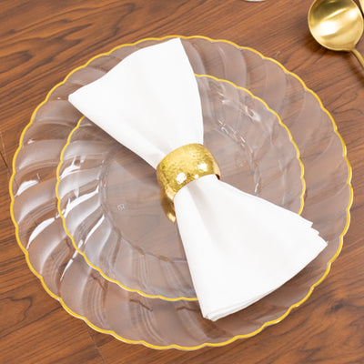 Elegant clear plates with gold trim and a white napkin holder on a wooden table.