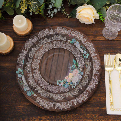 Decorative floral lace plates set on a rustic wooden table with candles and cutlery.